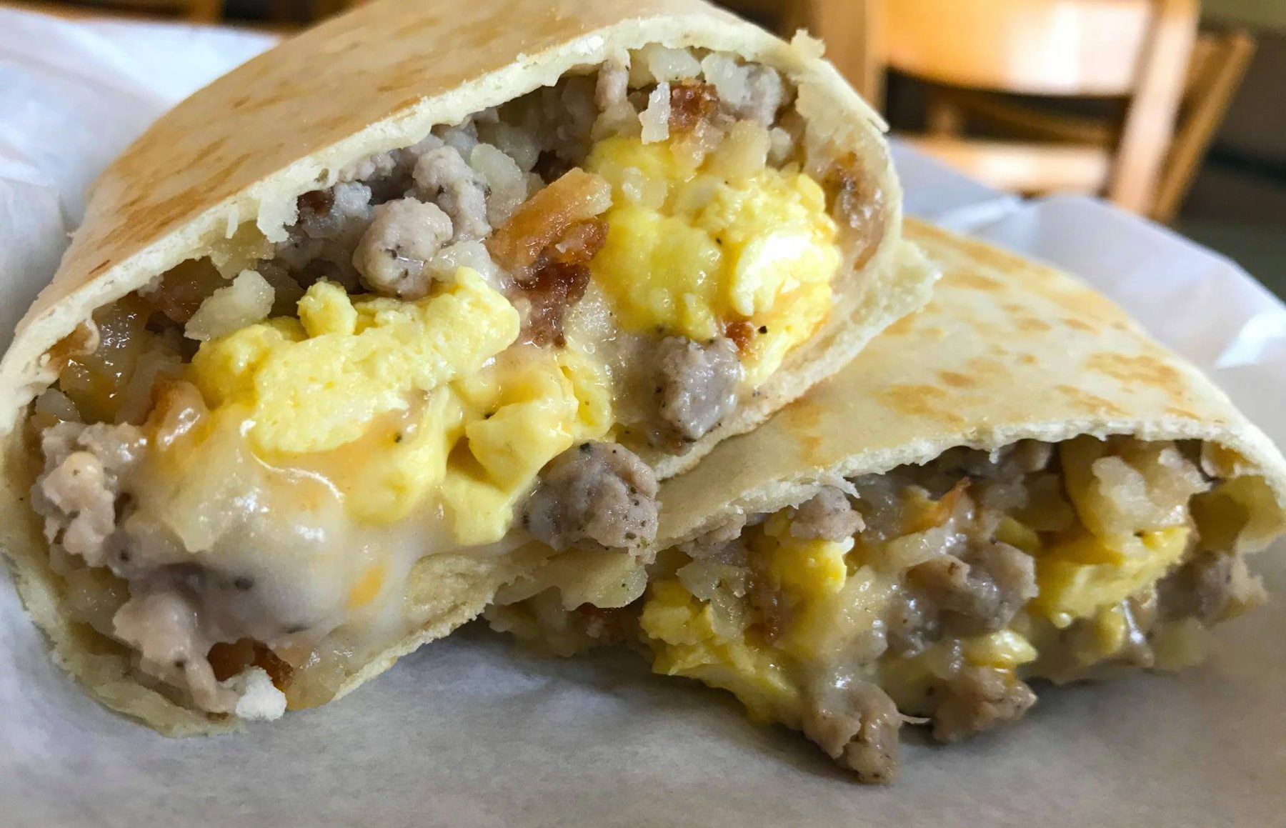 Breakfast wrap cut in half showing eggs, sausage, hash browns and cheese